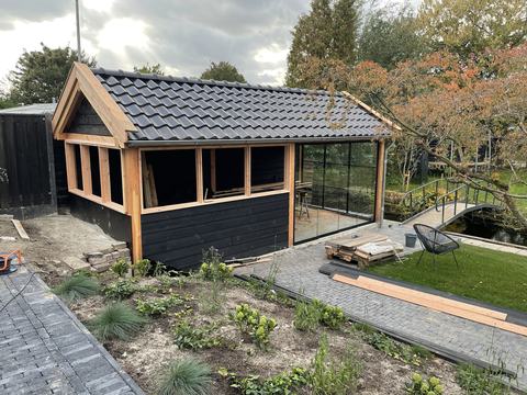 Overkapping met zwarte houten wanden, dakpannen en glazen wand