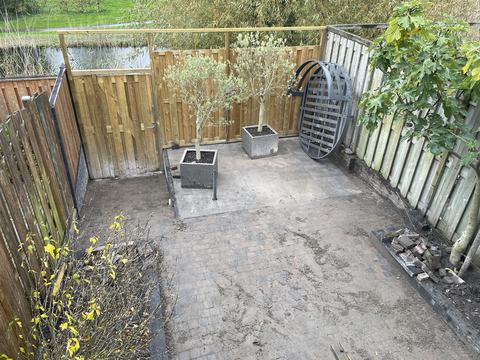 Achtertuin met verhoogd terras van grote tegels en klinkerbestrating